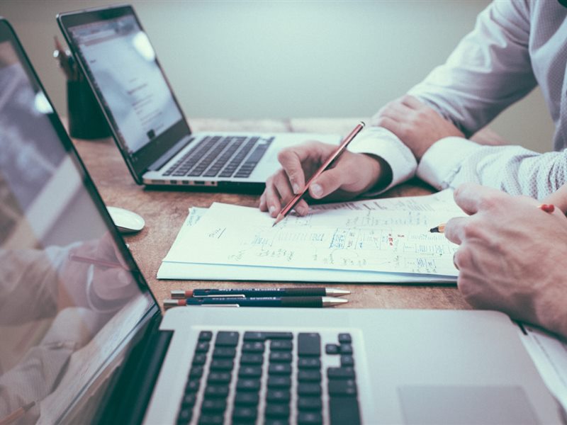 Duas pessoas planejando um negócio sobre a mesa com anotações e notebooks