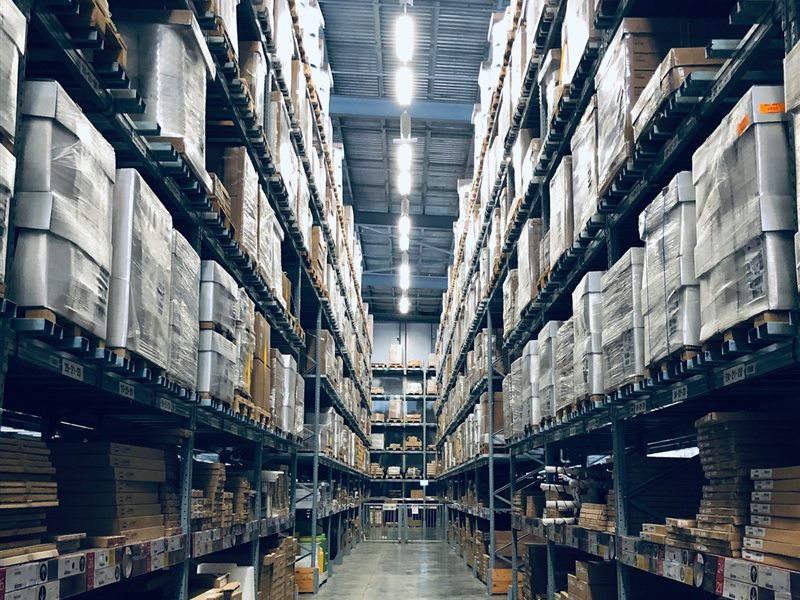 Interior de um galpão logístico com prateleiras altas e corredor central